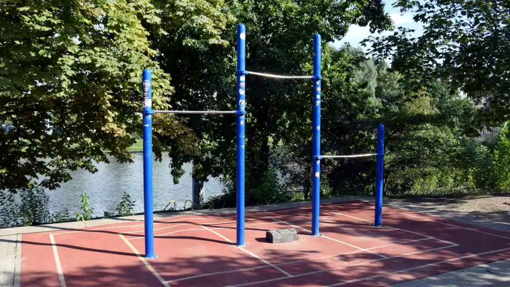 Drążki do zwisu i podciągania na zewnętrznym placu ćwiczeń nad rzeką